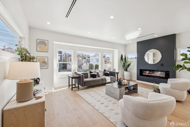 living area featuring a healthy amount of sunlight, a fireplace, and light wood-style floors