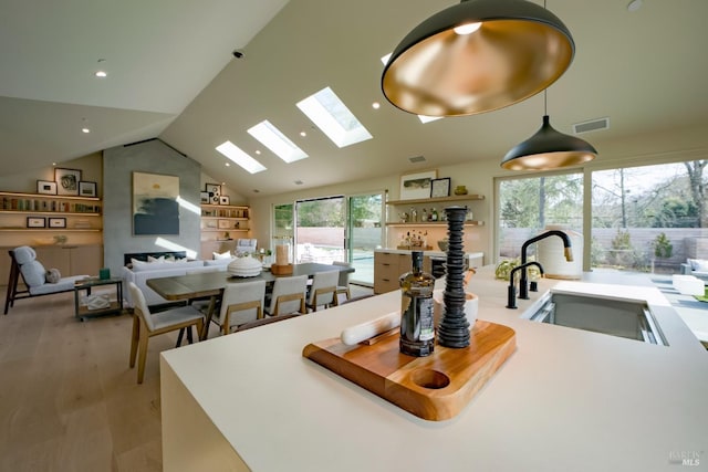 kitchen with vaulted ceiling, sink, a healthy amount of sunlight, and light hardwood / wood-style flooring