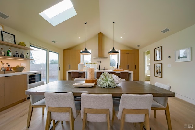 dining area featuring wine cooler, sink, light hardwood / wood-style flooring, and lofted ceiling