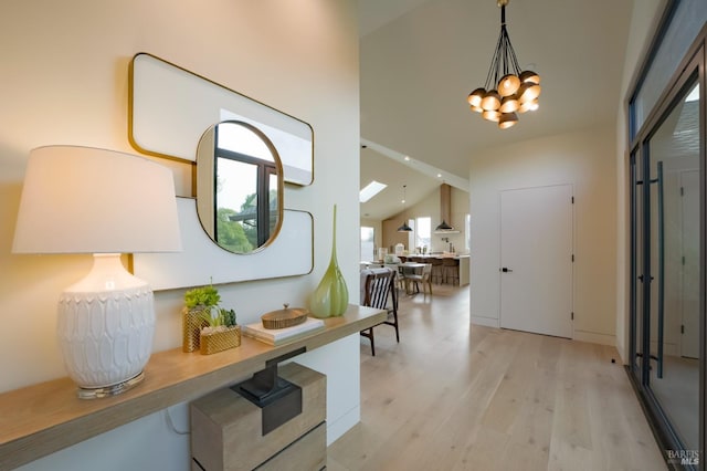 entryway featuring lofted ceiling, a chandelier, and light hardwood / wood-style floors