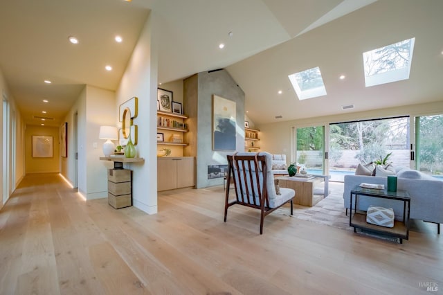 sitting room with lofted ceiling with skylight and light hardwood / wood-style floors