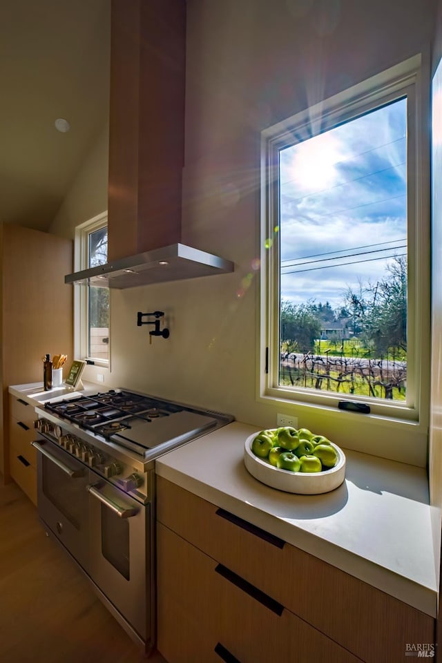 kitchen featuring a healthy amount of sunlight, island range hood, range with two ovens, and lofted ceiling