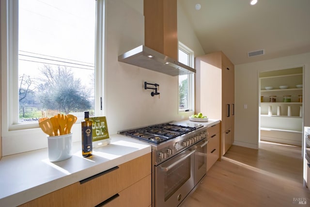 kitchen featuring light brown cabinetry, range hood, lofted ceiling, range with two ovens, and light hardwood / wood-style floors