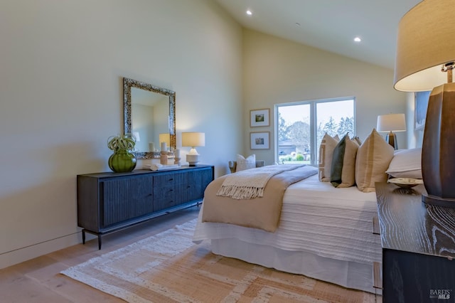 bedroom with wood-type flooring and high vaulted ceiling