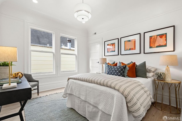 bedroom with baseboards, visible vents, and wood finished floors