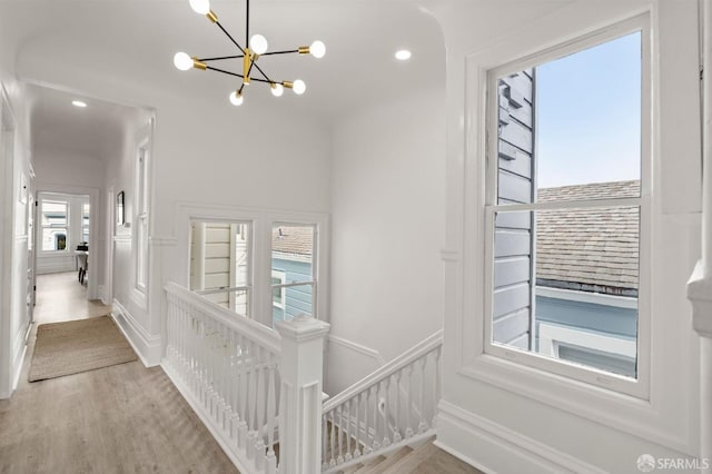 corridor featuring recessed lighting, an upstairs landing, an inviting chandelier, and wood finished floors