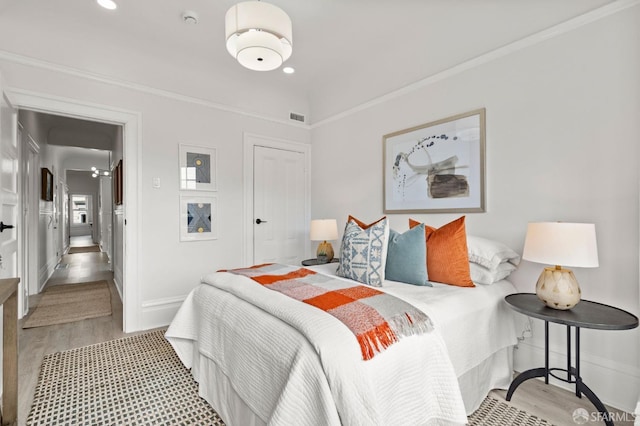bedroom with light wood-type flooring, ornamental molding, baseboards, and visible vents