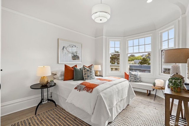 bedroom with crown molding, baseboards, and wood finished floors