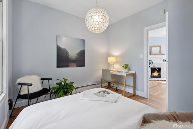 1250 Vallejo St Unit 7, San Francisco, CA 94109 - bedroom with wood finished floors, a warm lit fireplace, a baseboard heating unit, and an office area