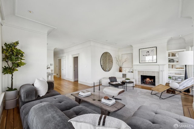 living room with wood-type flooring, crown molding, and a fireplace