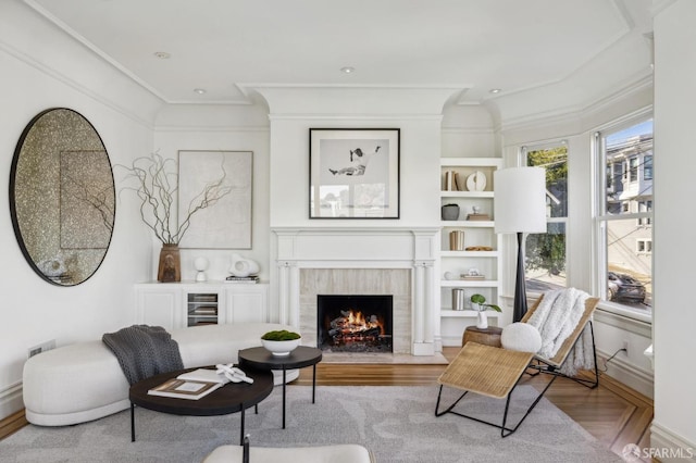 living area with light hardwood / wood-style flooring, crown molding, and a fireplace