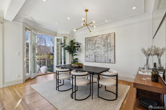 dining space with ornamental molding, a chandelier, and light hardwood / wood-style flooring