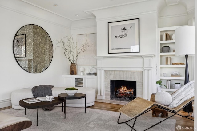 sitting room with light hardwood / wood-style flooring, ornamental molding, a fireplace, and built in features