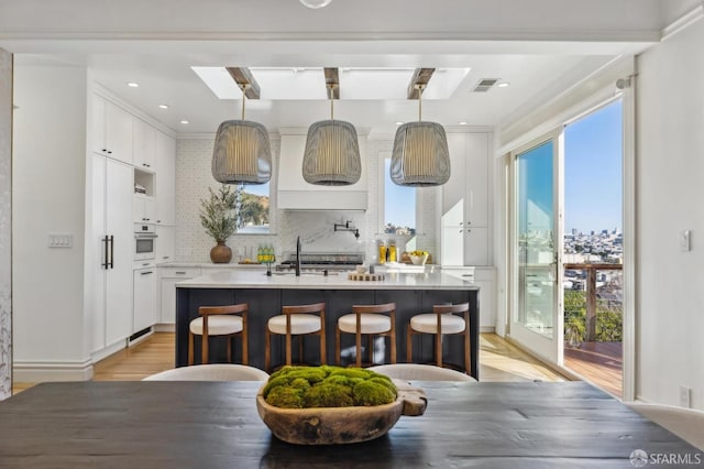 kitchen with pendant lighting, a wealth of natural light, white oven, and white cabinets