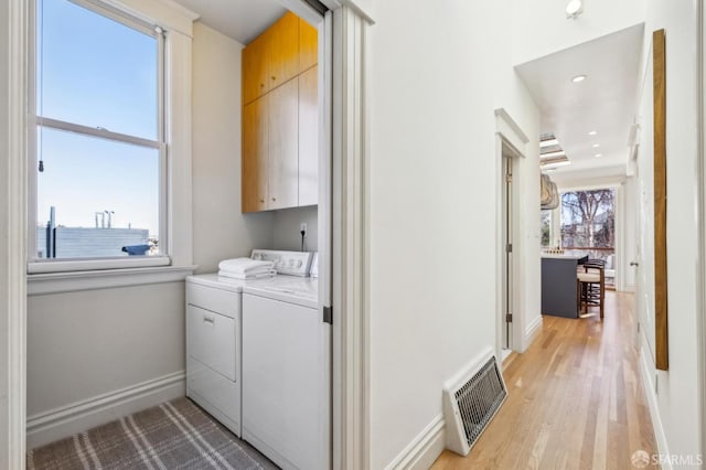 laundry room with cabinets, washer and clothes dryer, and light hardwood / wood-style floors