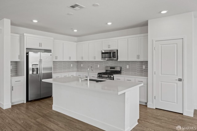 kitchen with white cabinetry, appliances with stainless steel finishes, a kitchen island with sink, and dark hardwood / wood-style floors