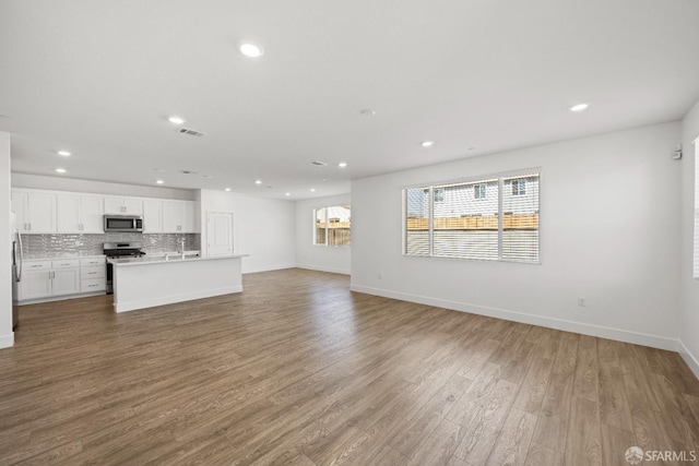 unfurnished living room with sink and hardwood / wood-style floors