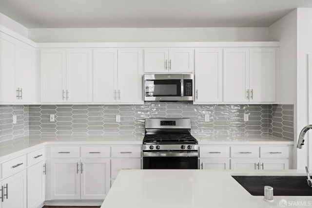 kitchen featuring sink, decorative backsplash, stainless steel appliances, and white cabinets