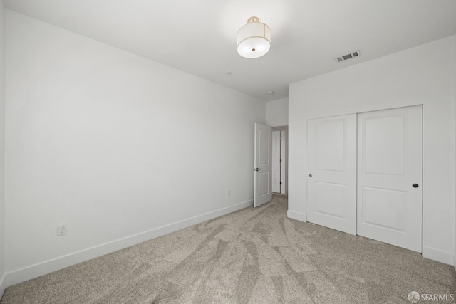 unfurnished bedroom with a closet and light carpet