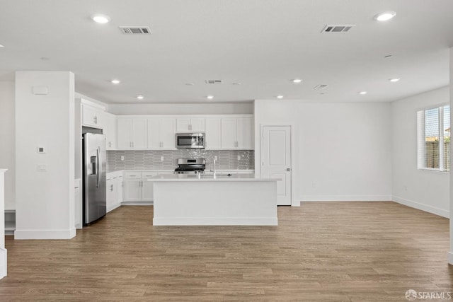 kitchen featuring stainless steel appliances, a kitchen island with sink, white cabinets, and light hardwood / wood-style floors