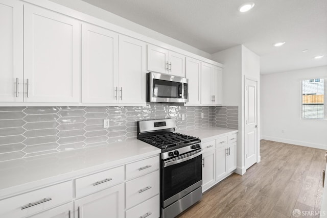 kitchen with stainless steel appliances, white cabinetry, tasteful backsplash, and light wood-type flooring