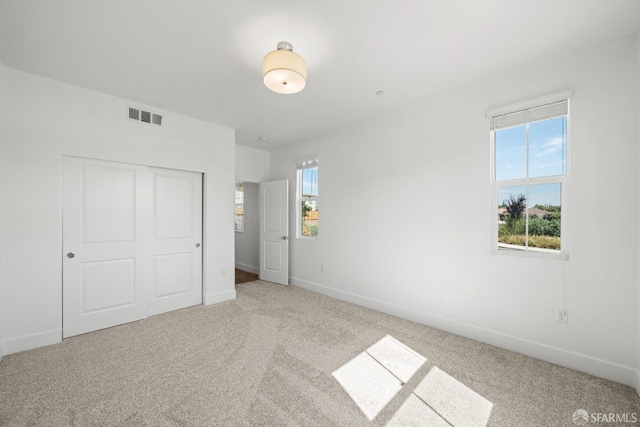 unfurnished bedroom featuring a closet and light carpet