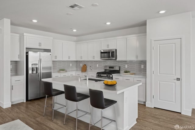 kitchen featuring white cabinetry, appliances with stainless steel finishes, and a center island with sink