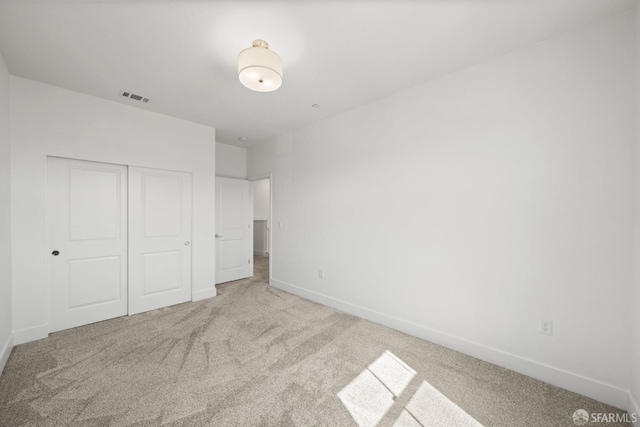 unfurnished bedroom featuring light carpet and a closet