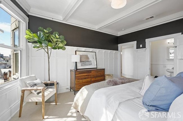 bedroom with crown molding, a decorative wall, beamed ceiling, and visible vents