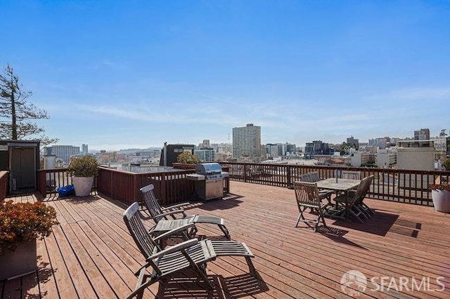 wooden terrace featuring outdoor dining space, a city view, and grilling area