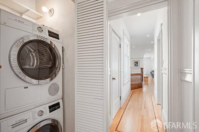 washroom featuring light wood-style flooring, stacked washer / drying machine, and laundry area