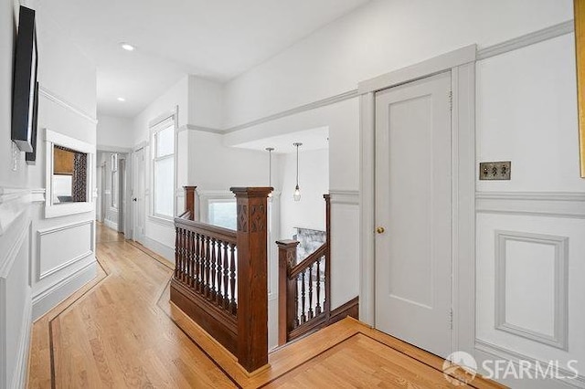 hall with light wood-style floors, an upstairs landing, and recessed lighting