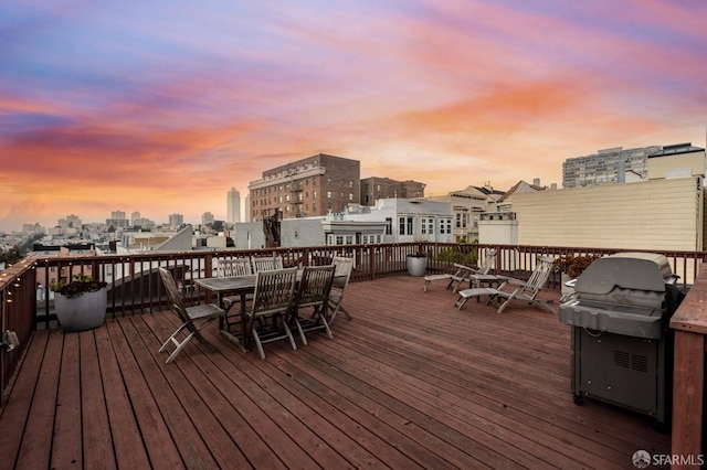 wooden deck with outdoor dining space, area for grilling, and a city view