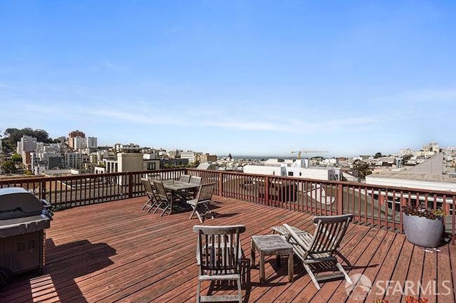 wooden terrace featuring outdoor dining space, a grill, and a view of city