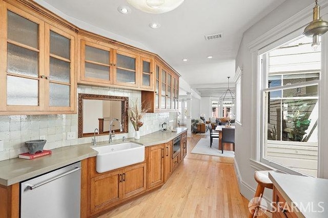 kitchen with glass insert cabinets, visible vents, brown cabinets, appliances with stainless steel finishes, and a sink