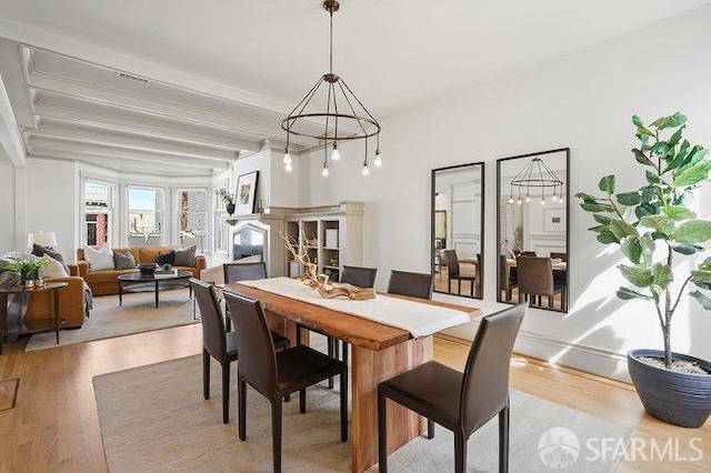 dining area with beam ceiling, light wood-type flooring, and a notable chandelier