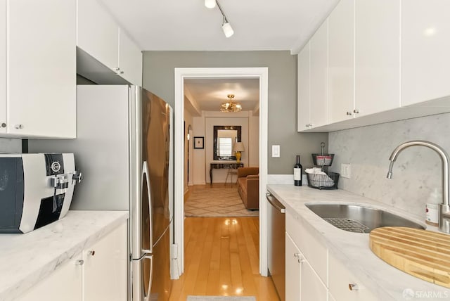 631 Ofarrell St Unit 702, San Francisco, CA 94109 - kitchen featuring a sink, appliances with stainless steel finishes, light wood-type flooring, tasteful backsplash, and white cabinetry