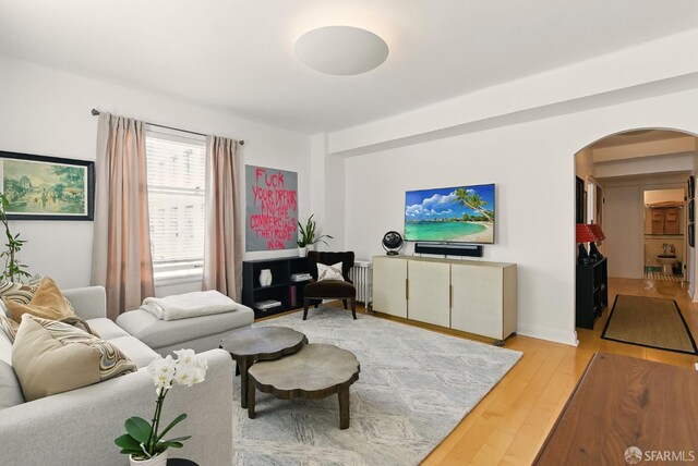631 Ofarrell St Unit 702, San Francisco, CA 94109 - living room featuring arched walkways, light wood-style flooring, and radiator heating unit