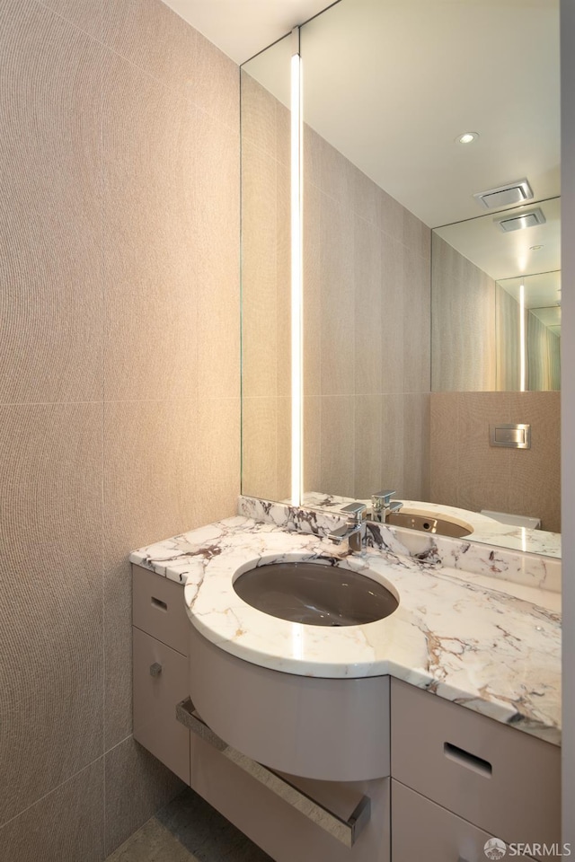 bathroom with vanity and tile walls