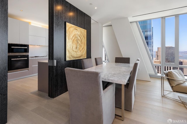 181 Fremont St Unit 58A, San Francisco, CA 94105 - dining room featuring light wood-style flooring, a wall of windows, a view of city, and recessed lighting