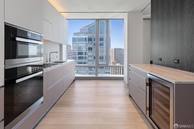181 Fremont St Unit 58A, San Francisco, CA 94105 - kitchen with beverage cooler, floor to ceiling windows, light wood-type flooring, stainless steel double oven, and modern cabinets