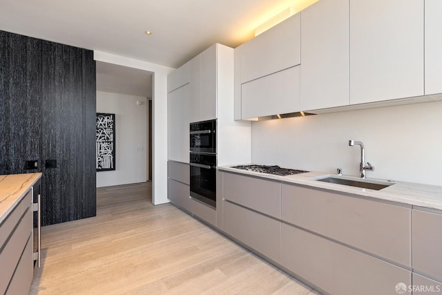 181 Fremont St Unit 58A, San Francisco, CA 94105 - kitchen with a sink, light wood-type flooring, gas stovetop, light stone countertops, and white cabinets