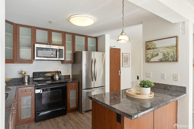 kitchen featuring pendant lighting, light wood-type flooring, kitchen peninsula, and appliances with stainless steel finishes