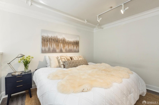 bedroom featuring dark hardwood / wood-style flooring, track lighting, and ornamental molding