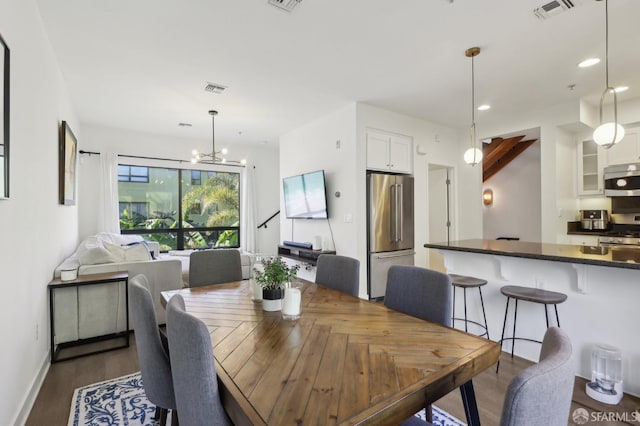 dining space featuring dark wood-type flooring, recessed lighting, visible vents, and an inviting chandelier