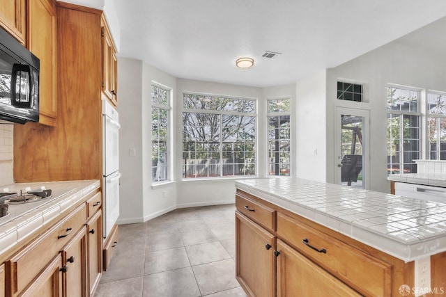 4737 Crestone Peak Dr, Antioch, CA 94531 - kitchen featuring tile countertops, light tile patterned floors, a healthy amount of sunlight, and white appliances