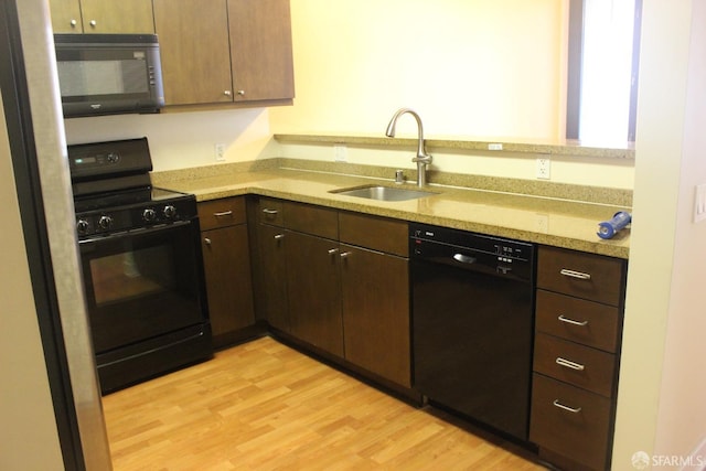 kitchen with dark brown cabinets, light wood-type flooring, sink, and black appliances