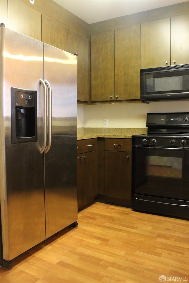 kitchen featuring black appliances, light hardwood / wood-style floors, and dark brown cabinets