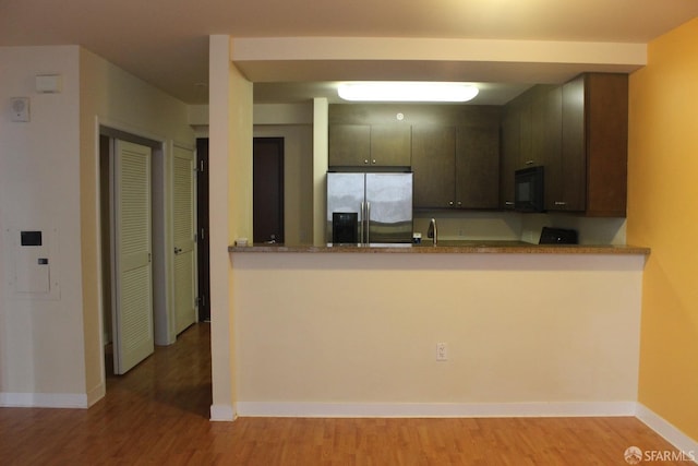 kitchen featuring dark brown cabinets, stainless steel refrigerator with ice dispenser, light wood-type flooring, and kitchen peninsula