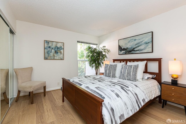 bedroom featuring a closet, light hardwood / wood-style floors, and a textured ceiling